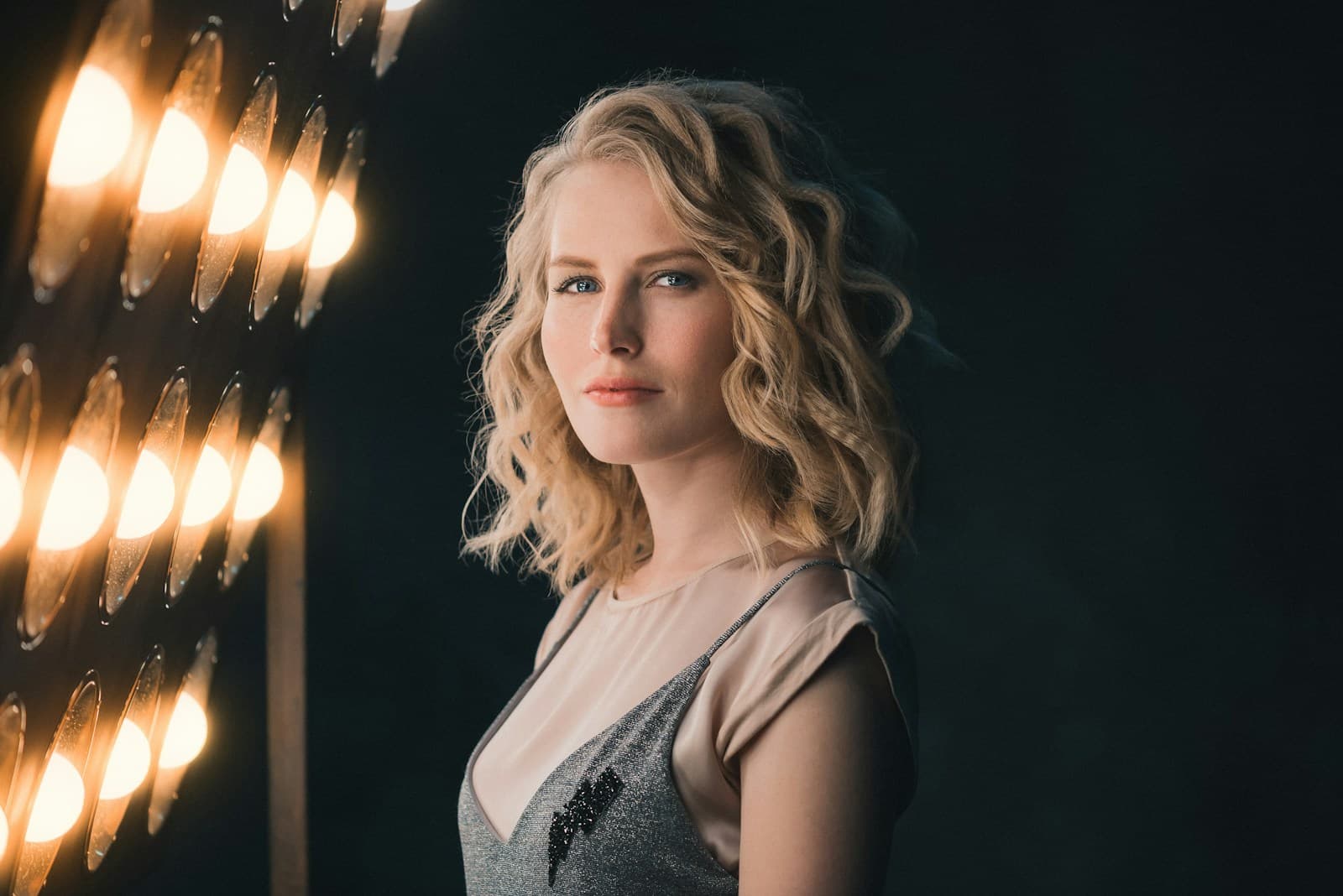 A model with softly curled blonde hair in a warm studio